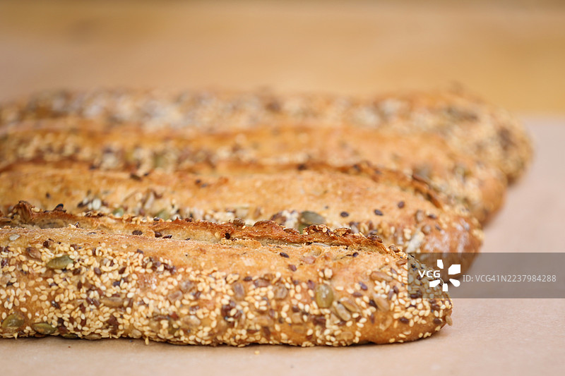 新鲜出炉的全麦法棍面包，上面撒有南瓜籽、黑芝麻和白芝麻，在户外农贸市场上售卖。图片素材