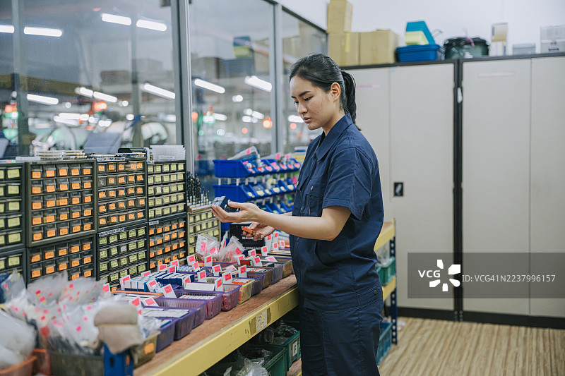 亚洲中国女技术员在工厂仓库整理零件图片素材