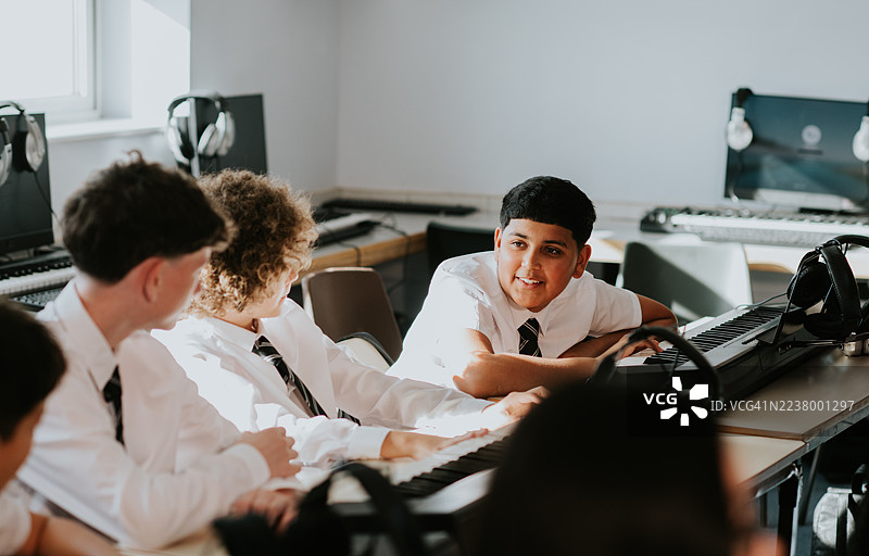 四个男孩坐在音乐教室的一排，进行着轻松活泼的讨论。图片素材