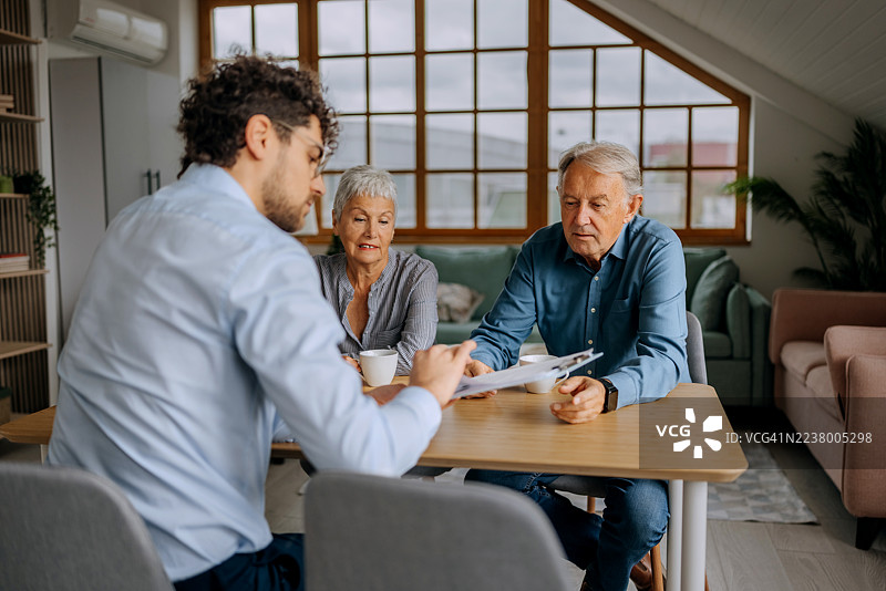 理财顾问在家中为一对老年夫妇提供咨询图片素材