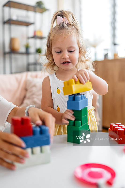 年轻母亲和女儿在客厅玩积木玩具图片素材