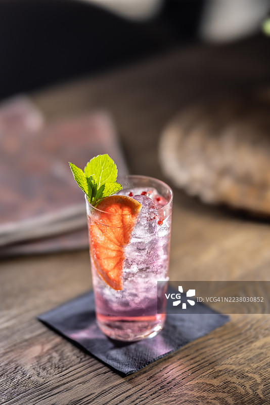 餐馆桌上的杜松子酒汤力鸡尾酒，配有冰块，并用葡萄柚调味。图片素材