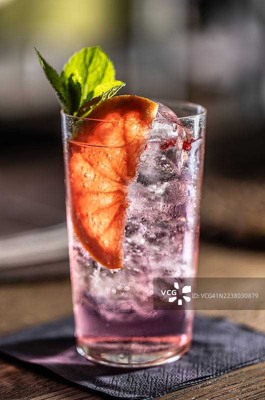 餐厅餐桌上的一杯杜松子酒汤力鸡尾酒，加了冰块，用葡萄柚调味。图片素材