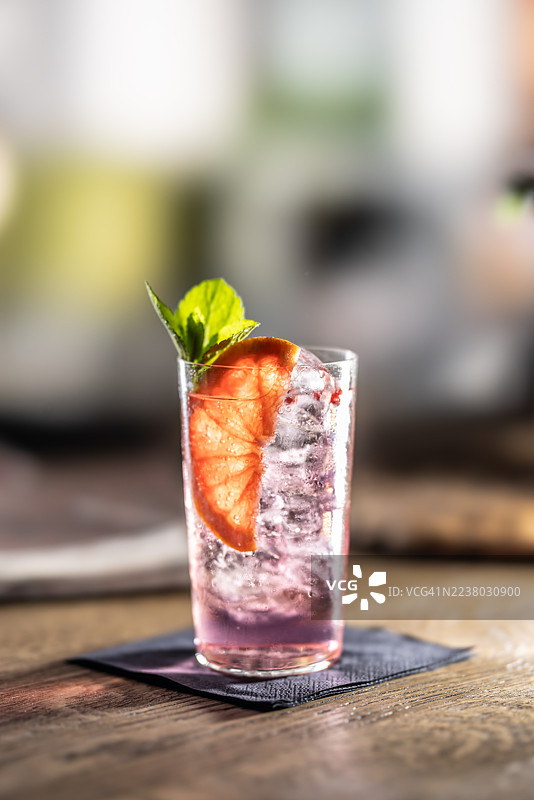 餐馆餐桌上摆放着一杯加了冰块的杜松子酒汤力鸡尾酒，用葡萄柚调味。图片素材
