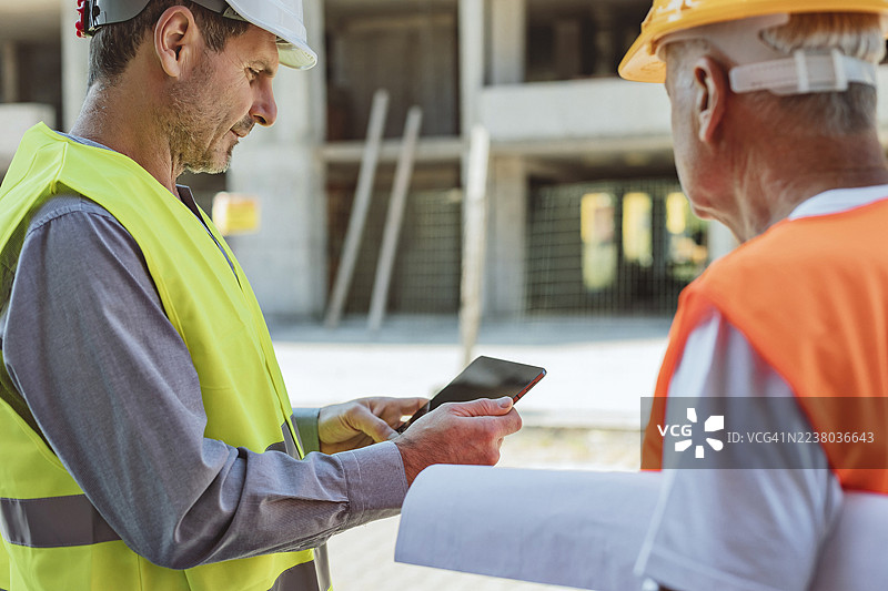 主管使用平板电脑向建筑工人简报图片素材