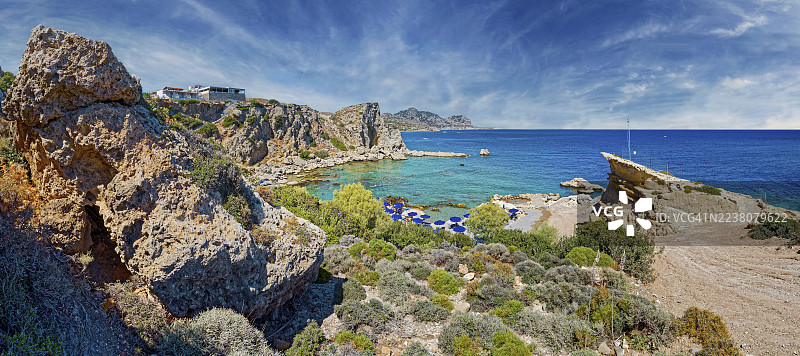 希腊罗德岛阿基安格洛斯斯特格纳的格兰德布鲁海滩,海滩上排满了遮阳伞,拥有蔚蓝的海洋和蓝色的天空的岩石海岸景观,格兰德布鲁。图片素材