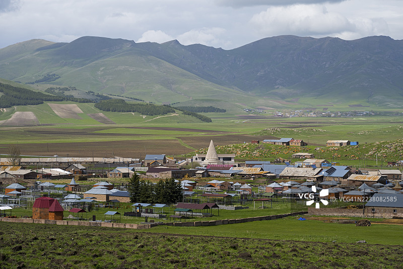 亚美尼亚阿拉加措特恩省Rya Taza村庄，坐落在绿色的山地景观中，点缀着零散的房屋和田野，以及一处亚兹迪神庙。图片素材