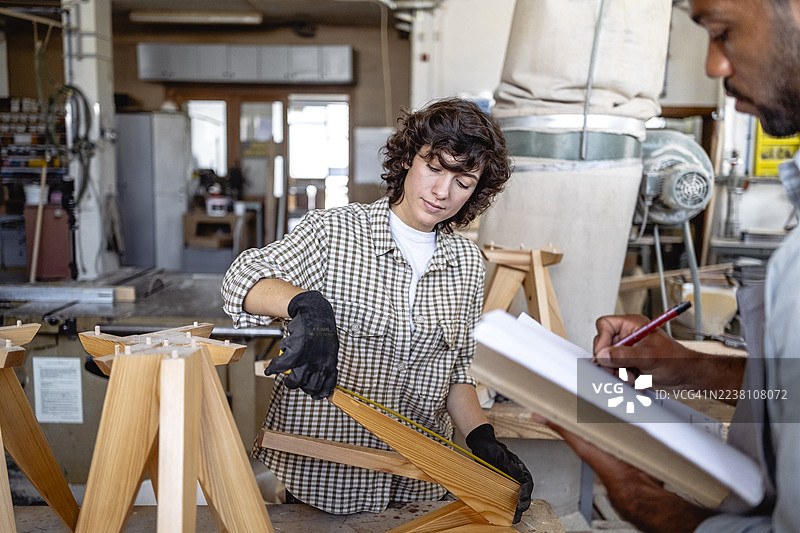 一群不同性别和种族的木匠在光线充足的工坊里合作设计家具图片素材