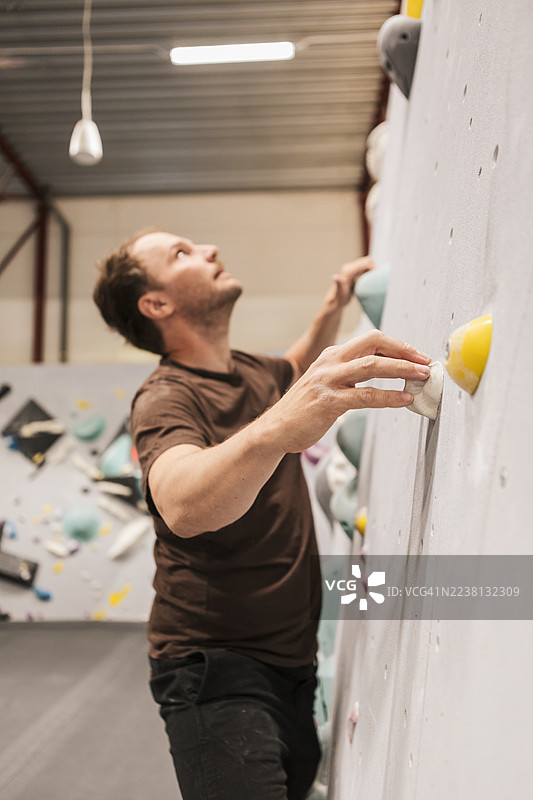 一位男士在攀岩中心进行抱石攀岩。图片素材