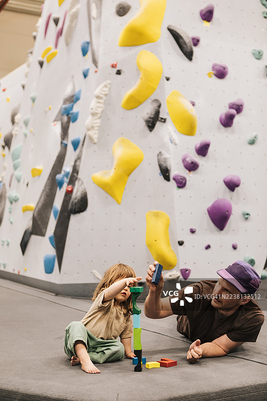 父亲在育儿假期间，在攀岩中心帮助女儿玩积木。图片素材