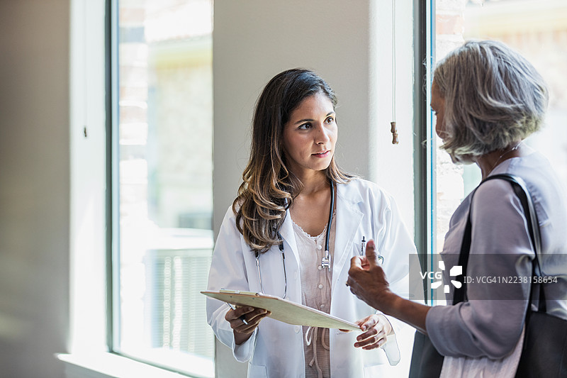 医生与一位忧心忡忡的老年女性讨论患者的健康信息图片素材