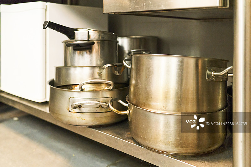 商业厨房不锈钢锅和煎锅放在架子上图片素材