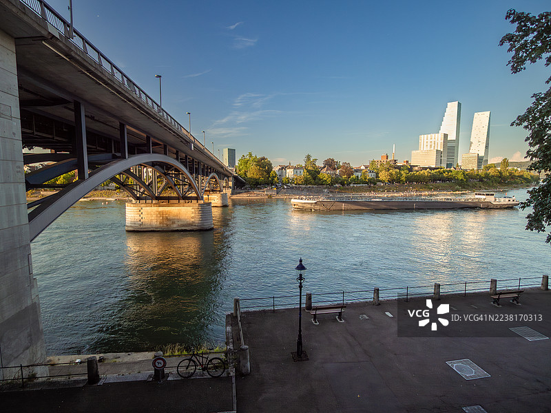 瑞士巴塞尔市中心莱茵河码头景观，远眺现代化的韦特施泰因桥、罗氏集团双塔摩天大楼以及河畔的公共长廊，巴塞尔城市州。图片素材