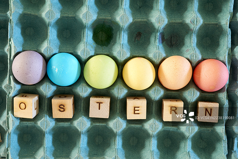 五颜六色的复活节彩蛋和拼写着“ostern”的木块图片素材