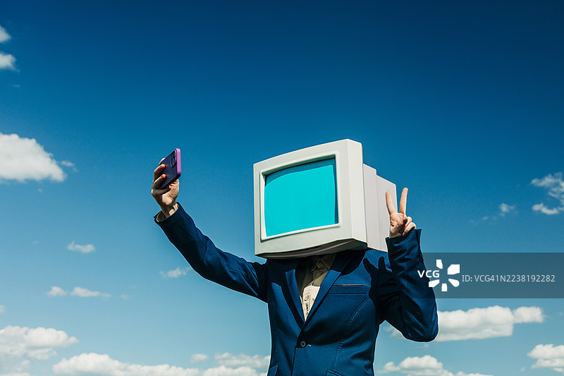身穿商务装的女性，头部是复古显示器，在蓝天下自拍图片素材