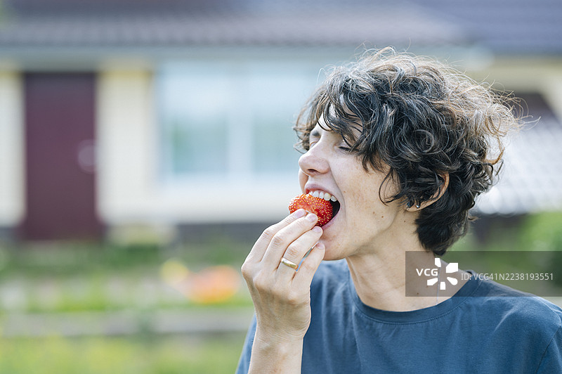 夏季收获时，女人在农场户外吃草莓图片素材