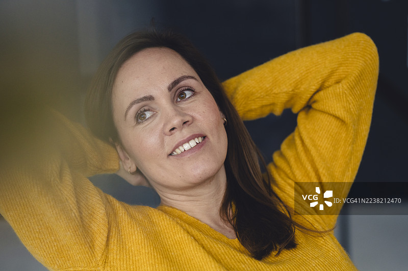 微笑的女性穿着黄色毛衣，在阁楼环境中放松。图片素材