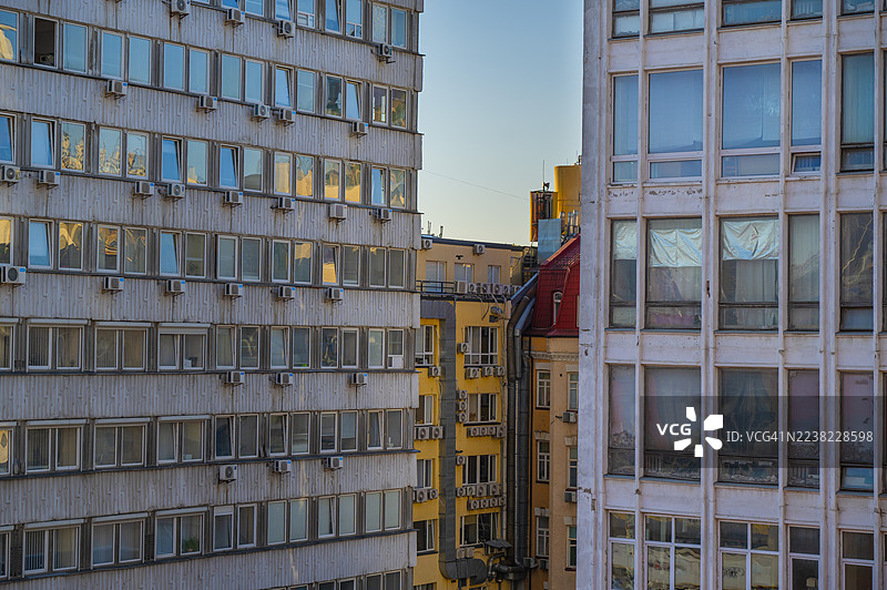 城市建筑密集地矗立在城市景观中，许多窗户反射着温暖的阳光，展示着混凝土外墙上的建筑和空调设备。图片素材