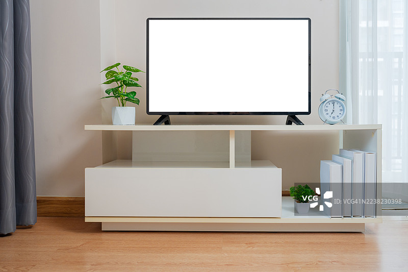 客厅里的电视机空白屏幕。白色墙壁背景的橱柜上放着智能电视。现代白色架子上的平板电视在家里。图片素材