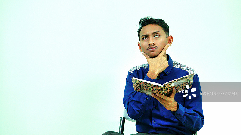 年轻外交官在商务会议中手托下巴沉思，手中拿着一本书图片素材