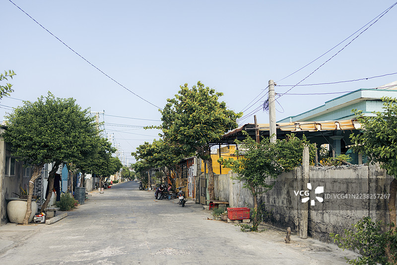 越南富贵住宅区宁静的街道，有树木、房屋和晴朗的天空。图片素材