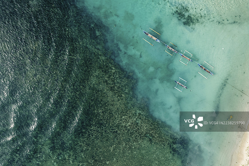印尼楠榜克鲁伊海岸线上，清澈碧绿的海水旁有一片沙滩，这是传统船只的鸟瞰图。图片素材
