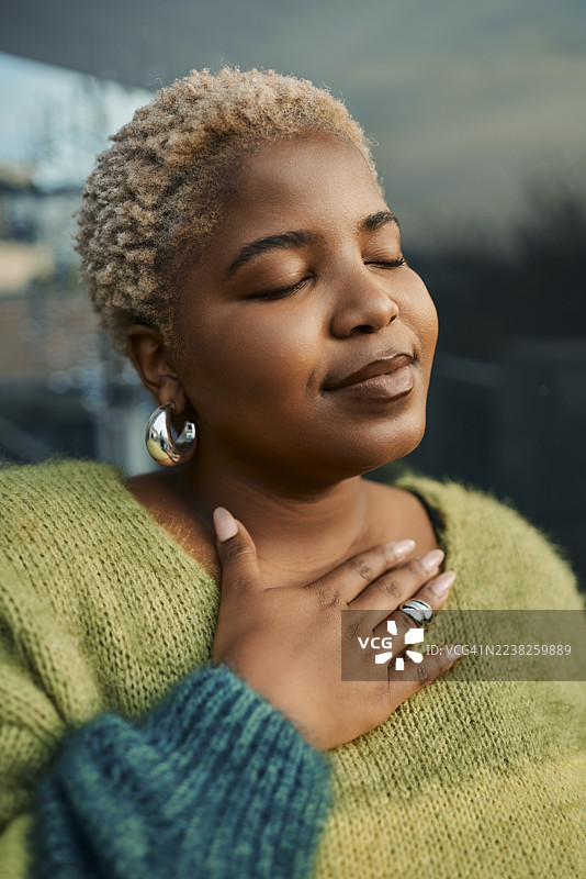 身穿绿色毛衣的非裔美国女性，在户外享受宁静的时刻图片素材