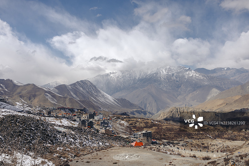 云层下的多云天空，山峰上点缀着白雪，村庄坐落在山谷中。木斯塘地区，安纳普尔纳，穆克蒂纳特，甘达基省，尼泊尔图片素材