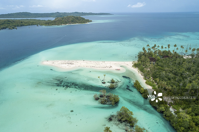 热带岛屿，拥有充满活力的蓝色海水和三姐妹棕榈树，周围环绕着清澈的海洋波浪。地点：印度尼西亚西苏门答腊省的曼塔威。图片素材