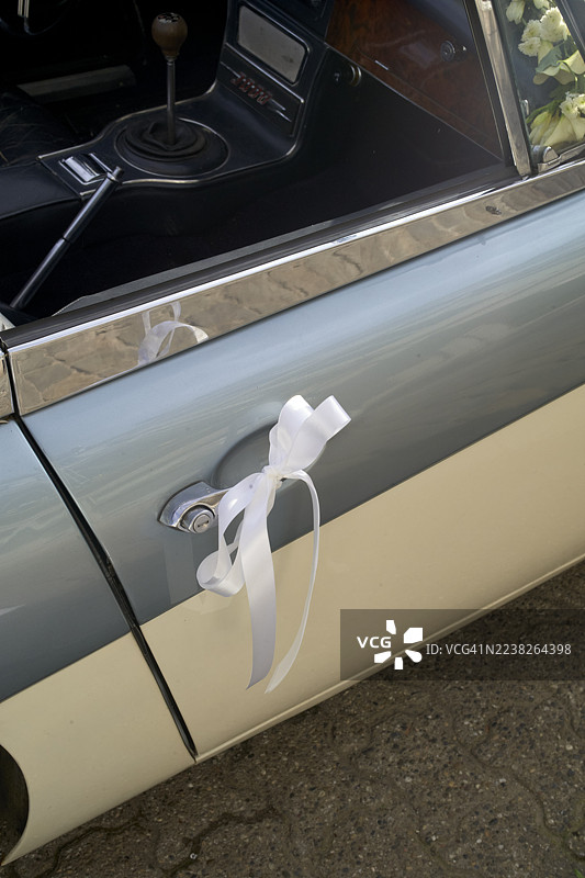 阳光明媚的一天，经典汽车门把手上系着白色丝带。比利时布鲁塞尔图片素材