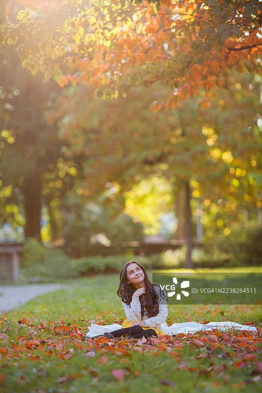 一个9岁小女孩的肖像，留着深色长发，穿着鲜艳的衣服。秋日公园里快乐的孩子。图片素材