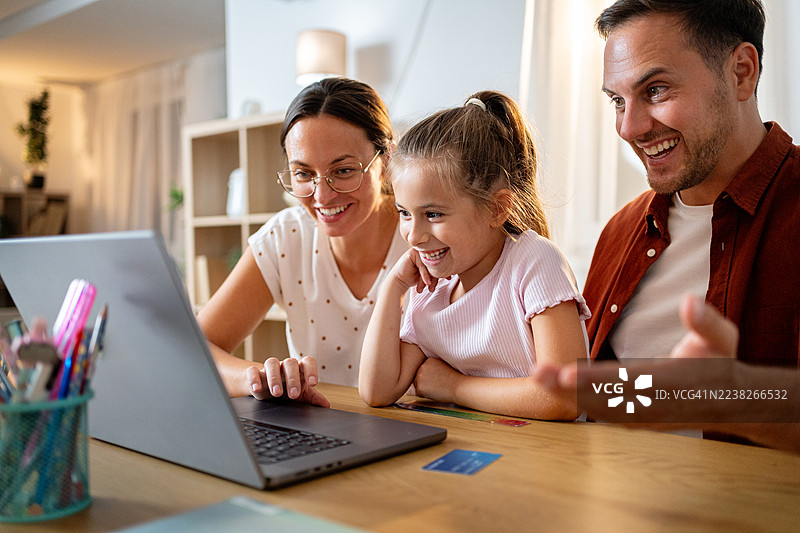 全家在家一起使用笔记本电脑，共享学习的快乐时光，脸上洋溢着笑容。图片素材