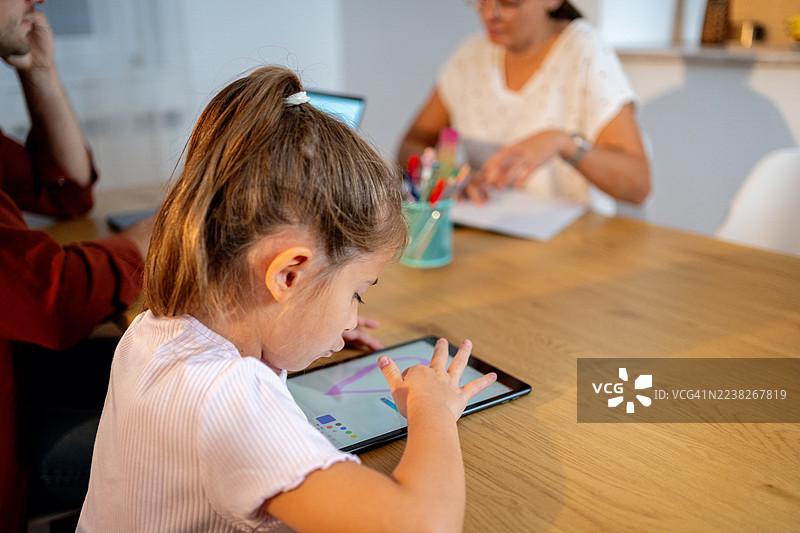 一家人居家办公：父亲在桌前使用笔记本电脑，女儿使用平板电脑图片素材