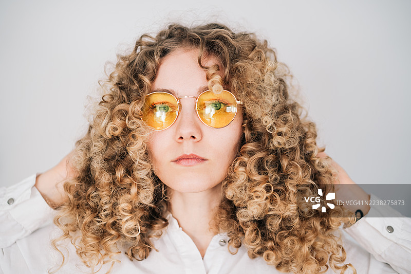 身穿白衬衫、留着卷曲金发的女性肖像图片素材