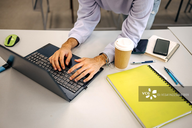 年轻人正在大学里学习，在笔记本电脑上打字浏览网页图片素材