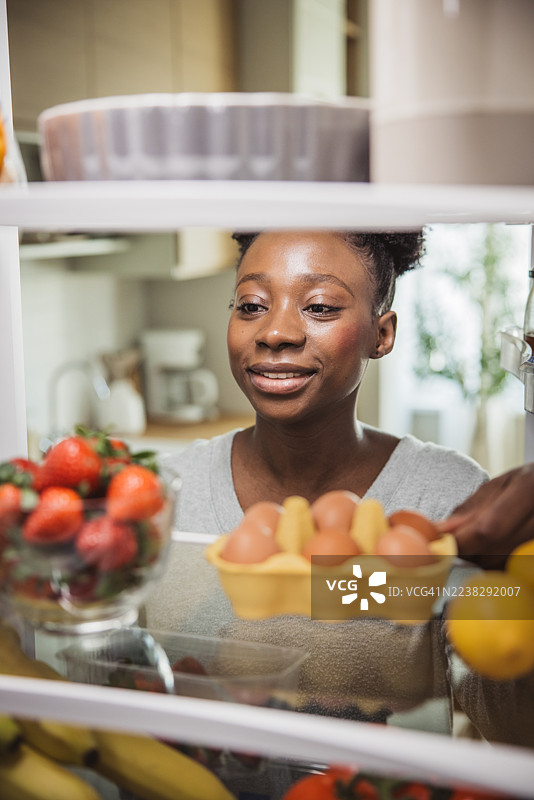 女人从装满食品的冰箱里拿取食物图片素材