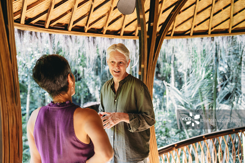 一对年长的夫妇在热带竹屋里交谈图片素材