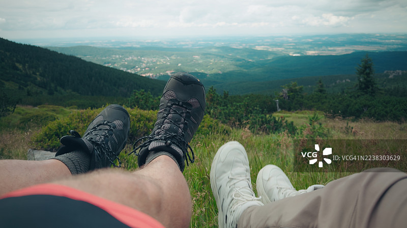 黑白鞋子，双腿在空中俏皮摆动，背景是美丽的远山景色。图片素材