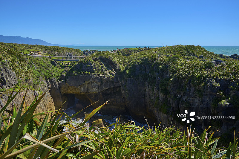 海景，绿色悬崖上的海岸小路和桥梁，煎饼岩，格雷茅斯，西海岸，南岛，新西兰图片素材