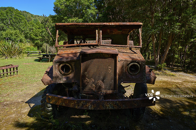 废弃的生锈卡车停在森林中，周围是质朴的景象，位于新西兰南岛马尔堡的布勒峡谷秋千桥、布勒河畔。图片素材