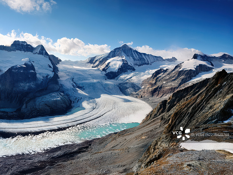 瑞士铁力士峰，恩格尔贝格，壮丽冰川在晴朗蓝天下蜿蜒穿过白雪皑皑的山脉，底部有绿松石色的融水湖泊，令人惊叹的航拍景象。图片素材
