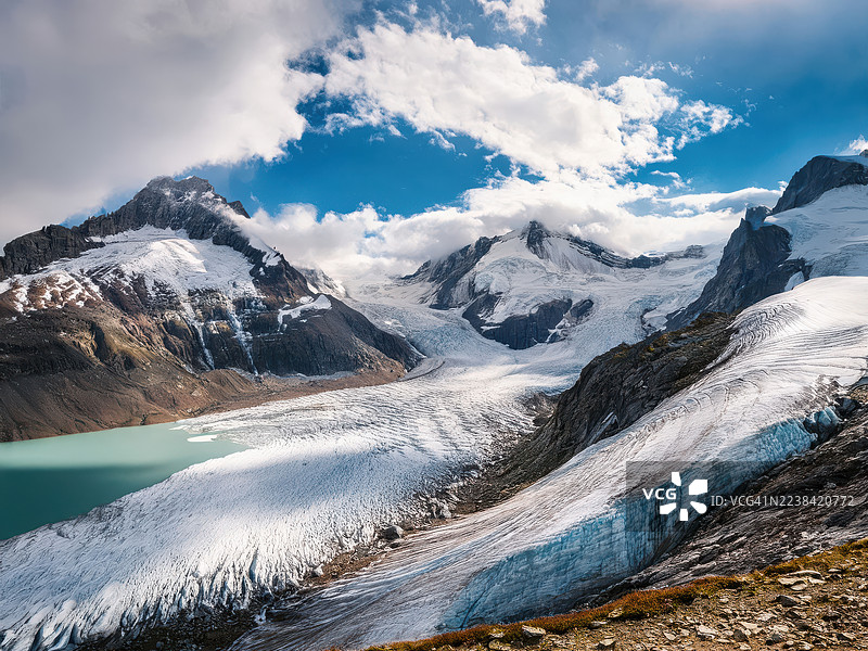 瑞士恩格尔贝格铁力士山，雄伟的雪山和广阔的冰川在戏剧性的天空下汇入宁静的绿松石湖泊图片素材