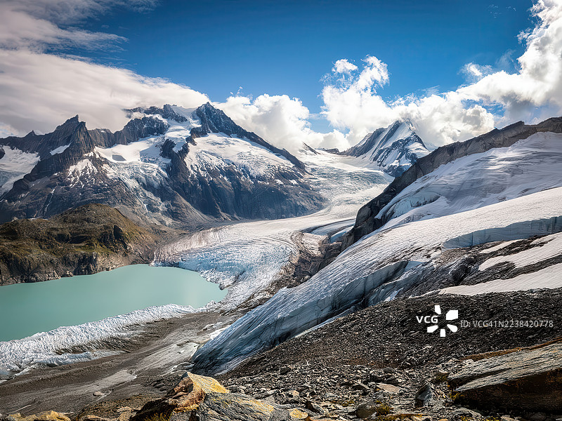 瑞士恩格尔贝格铁力士峰，在晴朗的蓝天下点缀着几朵白云，俯瞰着冰川湖被白雪覆盖的山峦环绕，展现出大自然的原始之美。图片素材