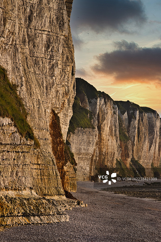 日落时分，戏剧性的海岸悬崖和鹅卵石海滩，天空色彩鲜艳图片素材
