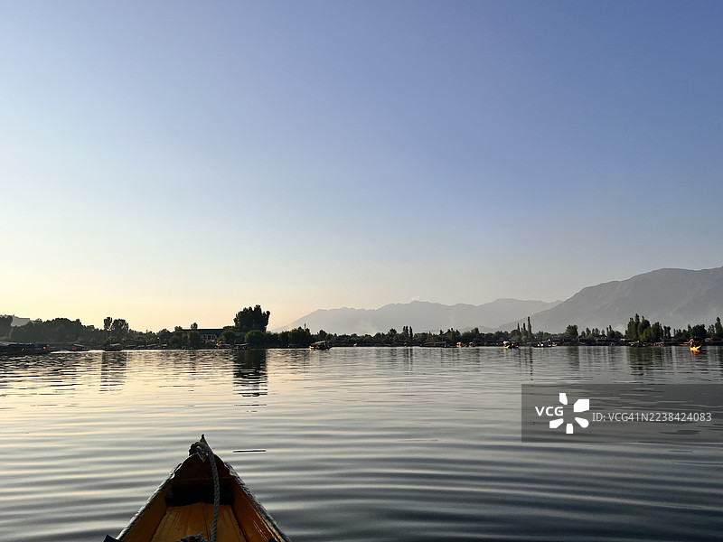 日出时分，远处群山和湖面上的船只构成宁静的湖景。图片素材