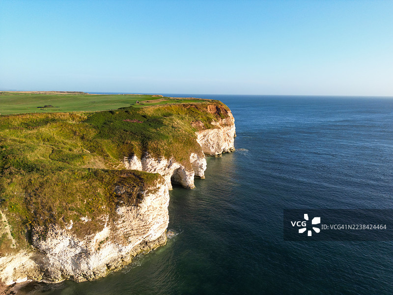 蔚蓝天空下，戏剧性的海岸悬崖俯瞰着广阔平静的大海，绿色的田野一直延伸到远方。图片素材