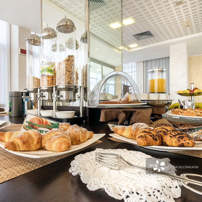 高角度拍摄的美味自助早餐，包括酒店或商店里的羊角面包、麦片和果汁。图片素材