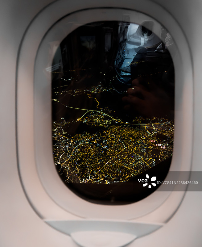 夜间从飞机舷窗俯瞰城市灯光，展示了美国的城市蔓延和交通网络，背景为斯凯山（Skye Mountains）。图片素材