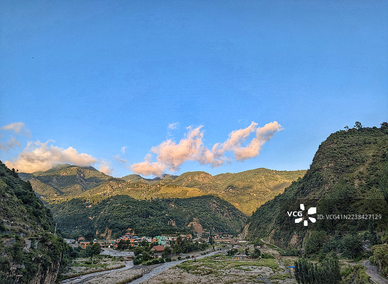 巴基斯坦阿伯塔巴德，雄伟的山谷，一条蜿蜒的河流，散落的村庄，在晴朗的蓝天下图片素材