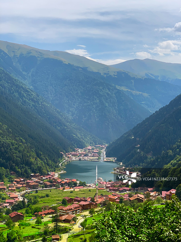 从高处俯瞰风景如画的山城，湖泊坐落在云层密布天空下的山谷中。图片素材